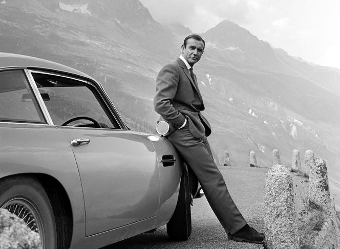 L’acteur Sean Connery pose en tant que James Bond à côté de son Aston Martin DB5, en 1964, dans une scène du film « Goldfinger ».